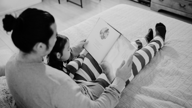 膝の上で子どもに絵本を読み聞かせている父親